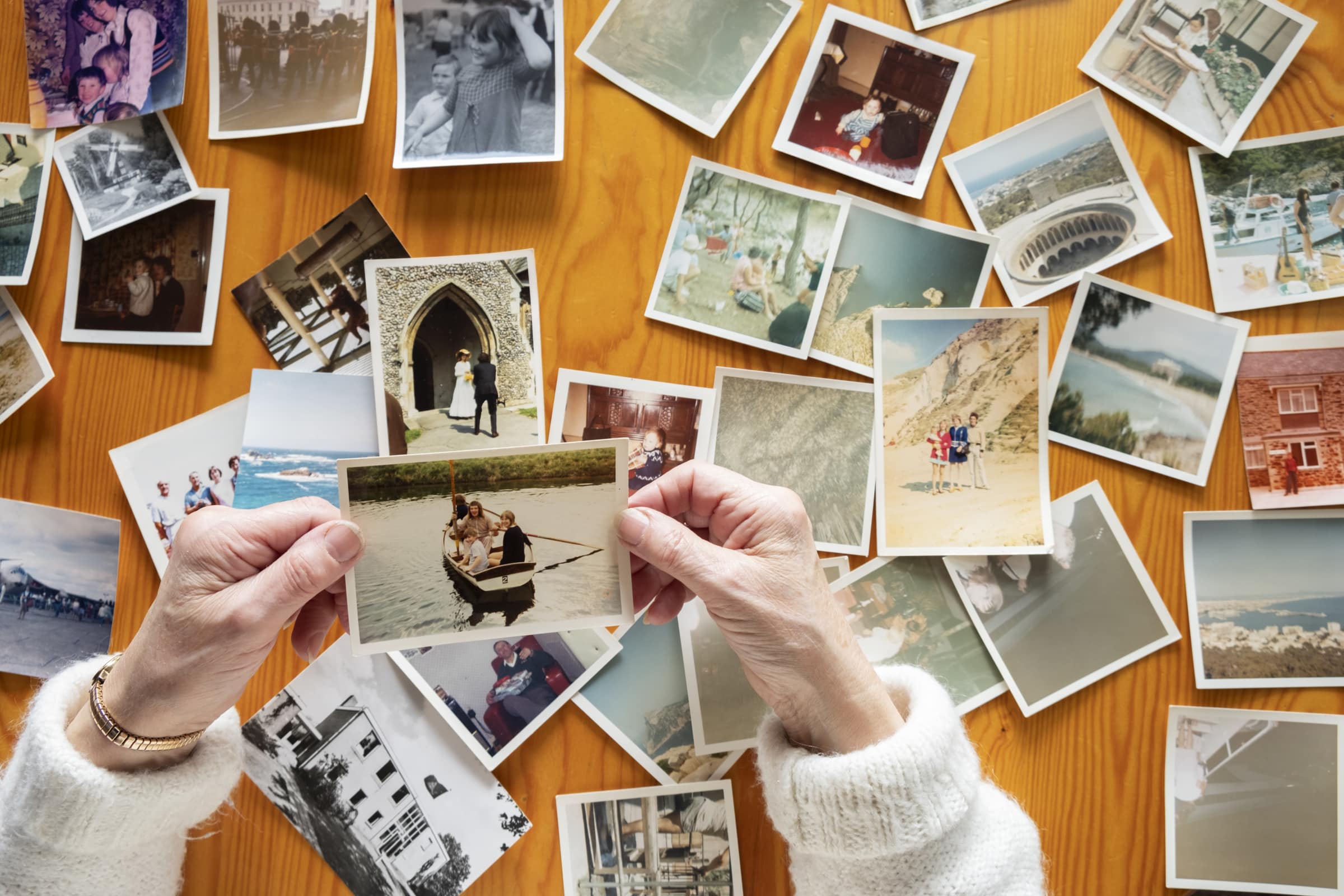 Elderly hands holding a collection of old family photographs